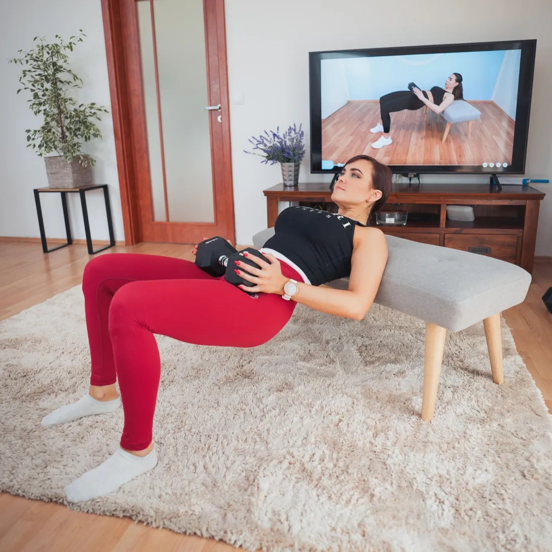 Žena cvičí doma podle videa na televizi